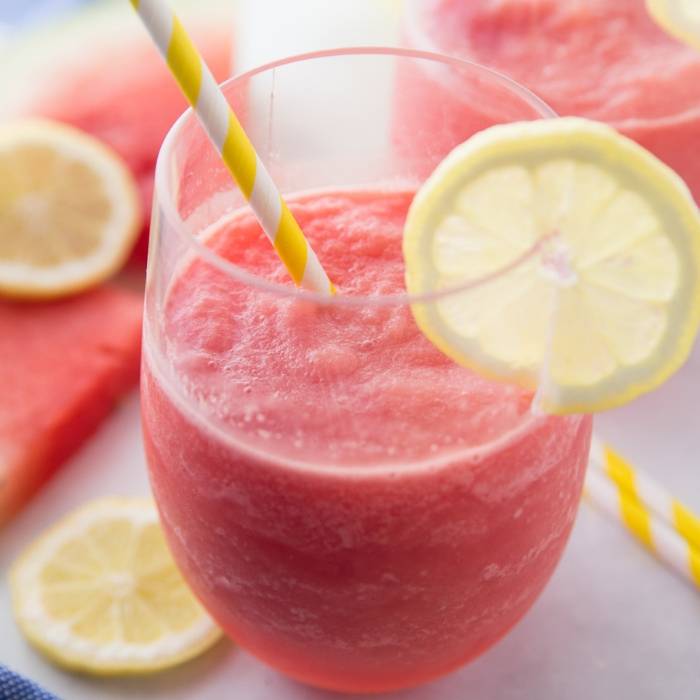 Frozen Watermelon Lemonade is so easy to make! I used a homemade lemonade but you are welcome to use store bought for these watermelon lemonade slushies. #watermelon #slush #slushies #lemonade #homemade #frozen #summerdrink #easy #partydrink watermelon lemonade slushies in a glass with lemon peel