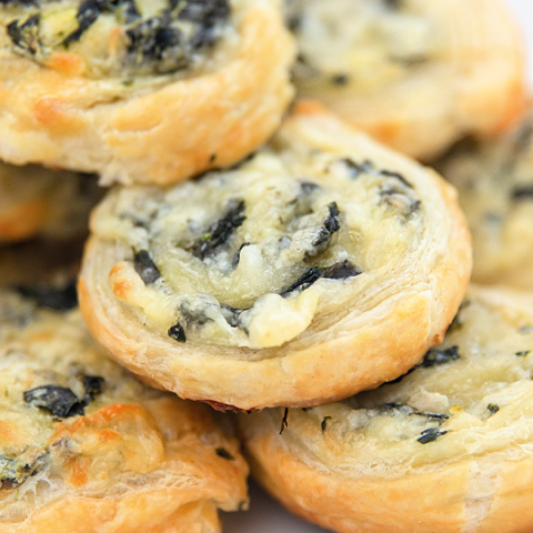 creamy spinach pinwheels arranged on a white serving tray
