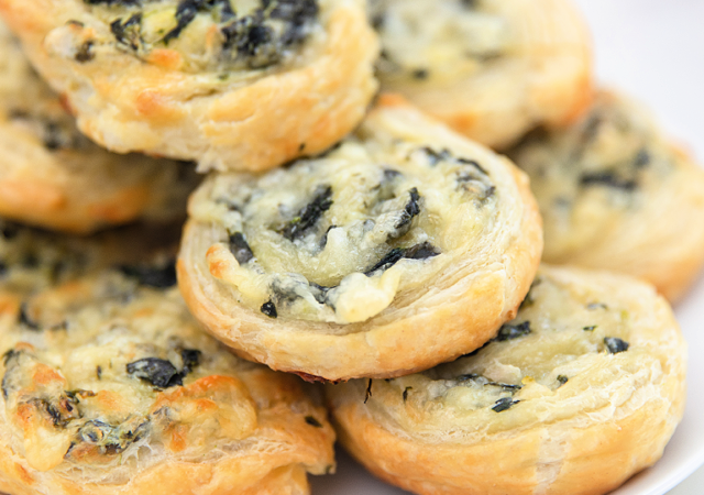 creamy spinach pinwheels arranged on a white serving tray