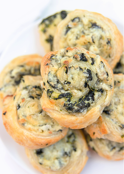 creamy spinach pinwheel stacked on a serving tray