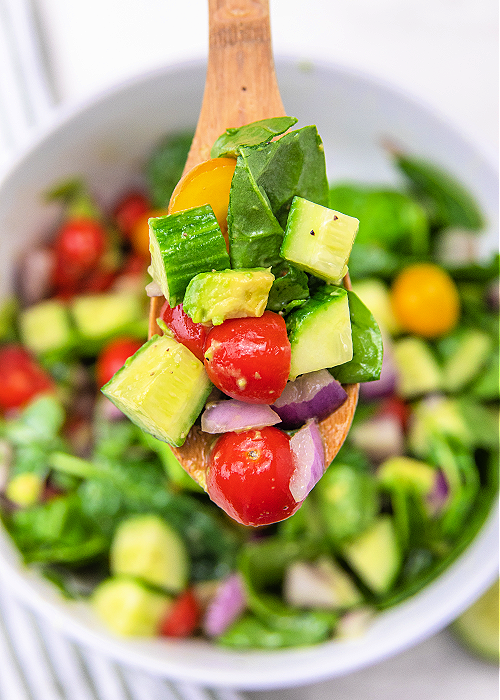 cucumber tomato salad on a wooden serving spoon
