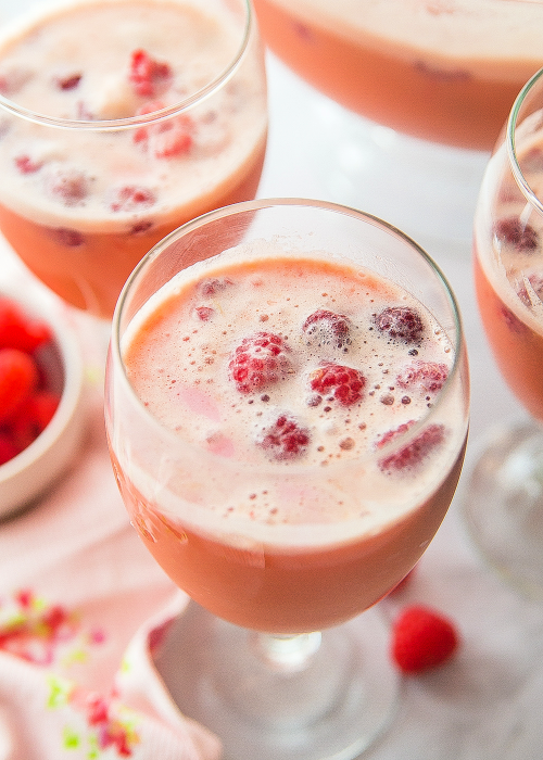 sparkling valentine punch in a goblet with raspberries floating in it for garnish