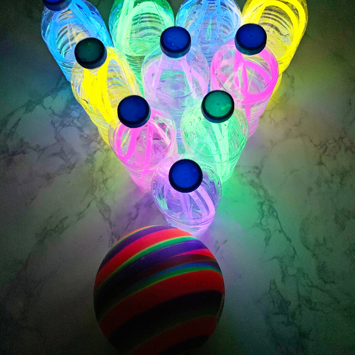 Glow in the Dark Bowling made from used water bottles and glow in the dark necklaces. A fun and easy indoor activity for kids that will make the evening loads of fun! #passion4savings #indoor #rainyday #activity #glowsticks #bowling #indoorbowling #diy #craft #activity Glow In The Dark Bowling Pins