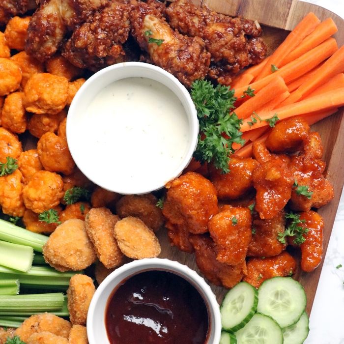 mix of chicken wings on a board with sauces 