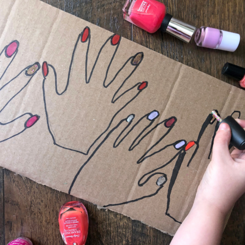 kid painting nails on cardboard drawing