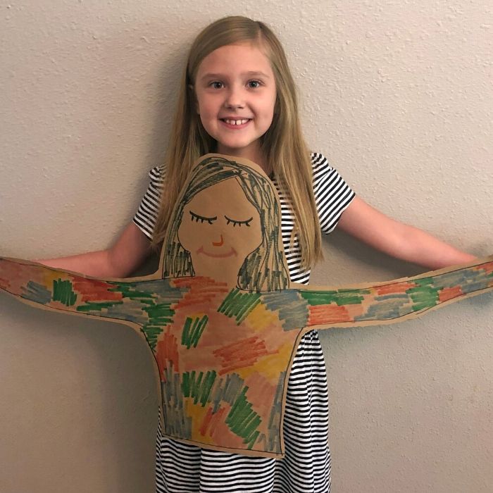 girl holding a cut out drawing of herself