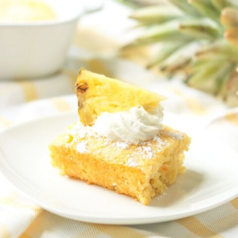 slice of pineapple cake on white plate with pineapple in background