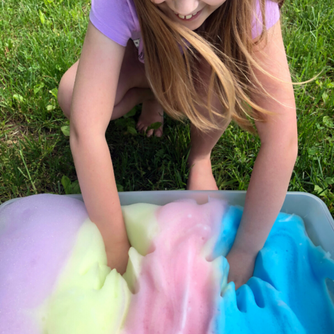 soap foam in a bin outside with kid playing