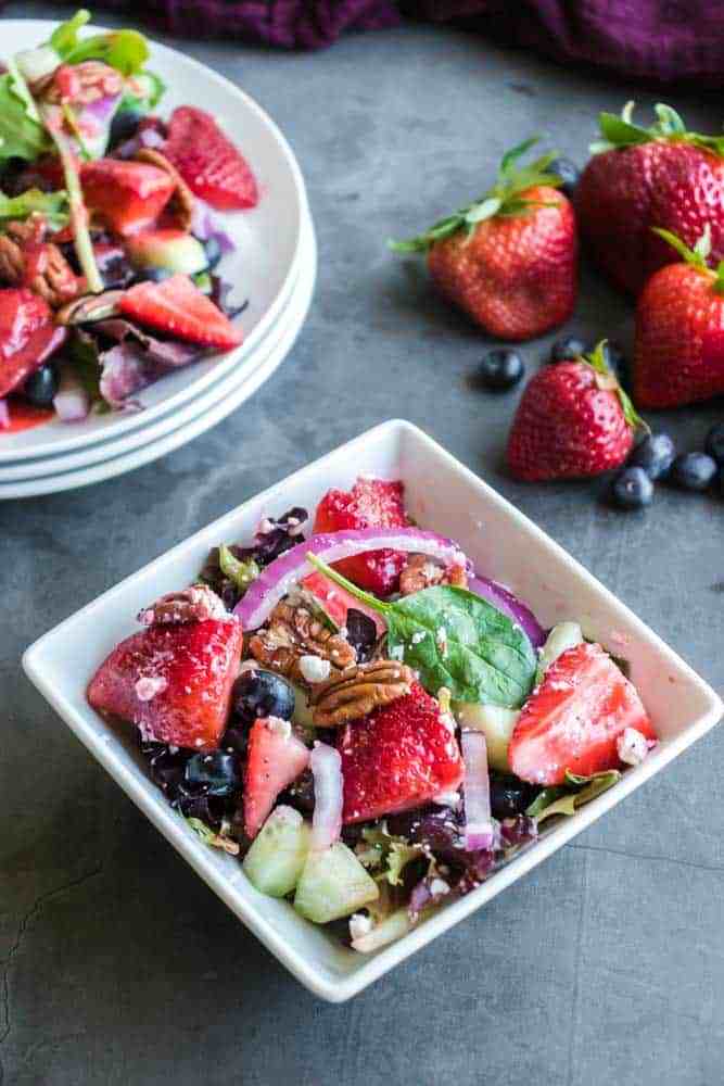 strawberry salad in a square bowl with fruit by it 