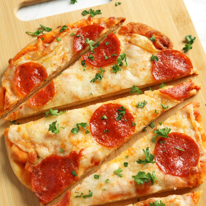 Flat Bread Pizza is the easiest weeknight flatbread pizza recipe. Whip this up for a quick and easy 20 minute dinner the whole family will enjoy. #passion4savings #pizza #flatbread #naan #pepperoni #easy #20minute #dinner #familyfriendly flat bread pizza on cutting board