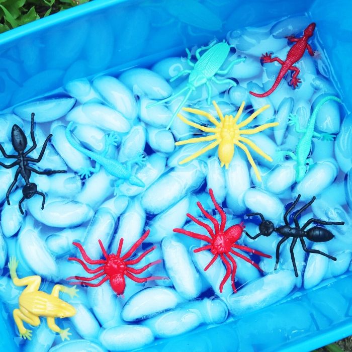 sensory bin full of ice and plastic bugs 