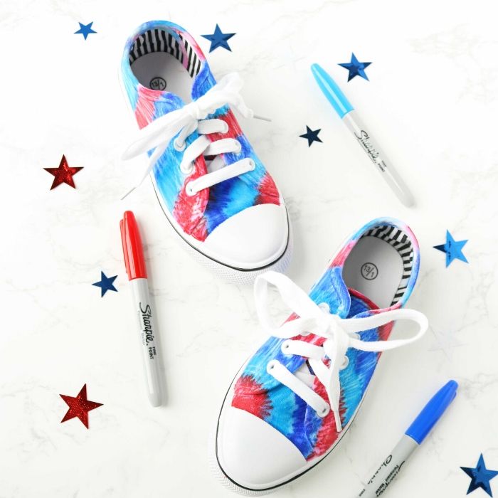 Sharpie Patriotic Tie Dye Shoes is the perfect way to get your shoes ready to watch the 4th of July fireworks. Grab a pair of white shoes, some markers and get to creating this fun patriotic custom shoe. A fun red white and blue shoes craft! #passion4savings #4thofjuly #craft #diy #project #redwhiteblue #festive #sharpie #whiteshoes #shoecraft sharpie colored shoes with pens by it