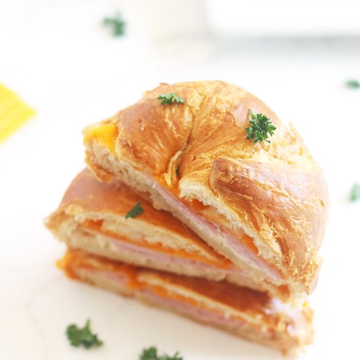 ham and cheese croissant sandwich sliced and topped on each other 