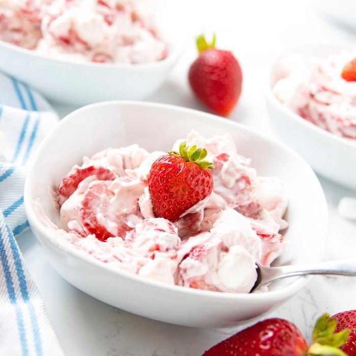 strawberry cheesecake salad in a bowl with strawberries by bowl 