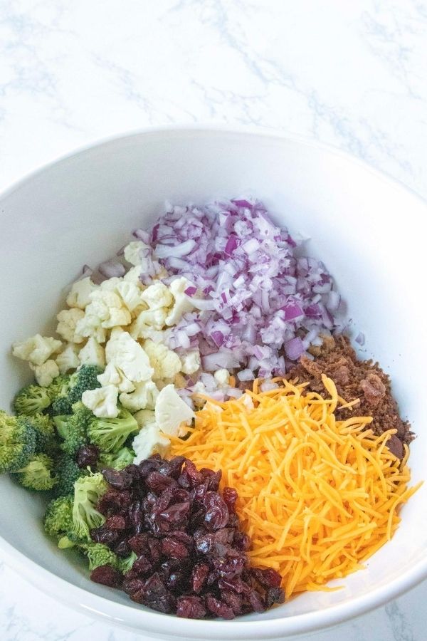 Broccoli Cauliflower Salad is the ultimate side dish or potluck dish. Broccoli, cauliflower, cranberries all mixed in a creamy and sweet sauce. #broccoli #cauliflower #easy #sidedish #holiday #Potluck #passion4savings #creamysauce #Homemade #fresh #vegetables broccoli cauliflower salad ingredients in a bowl