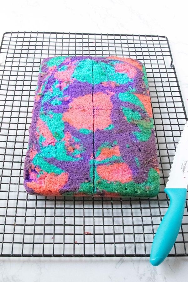 layered cake on cooling rack being cut into 4 pieces