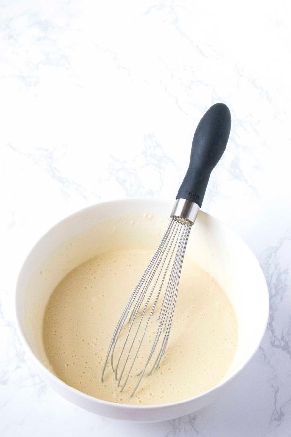 pancake batter in a white bowl with whisk