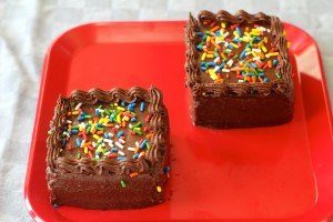 vegan chocolate cake and frosting on red plate 