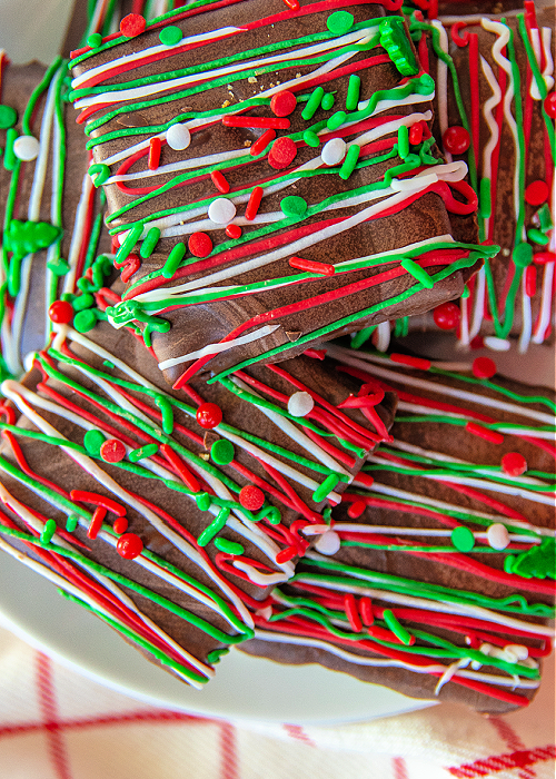 a close up of chocolate dipped graham crackers with different holiday colors of chocolate drizzled across the top