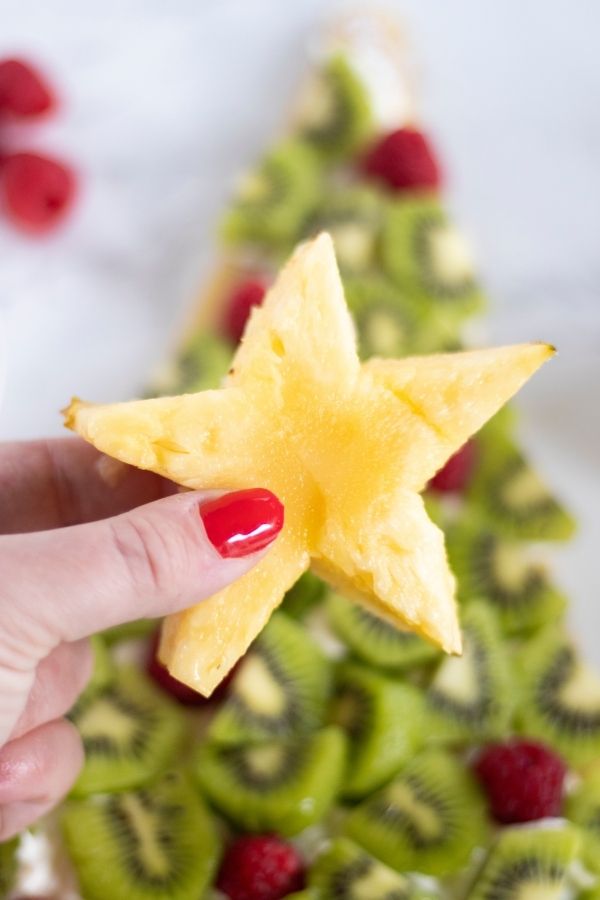 christmas dessert with star shaped pineapple being held 