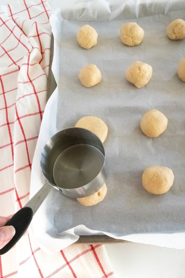 pushing down cookies with measuring cup