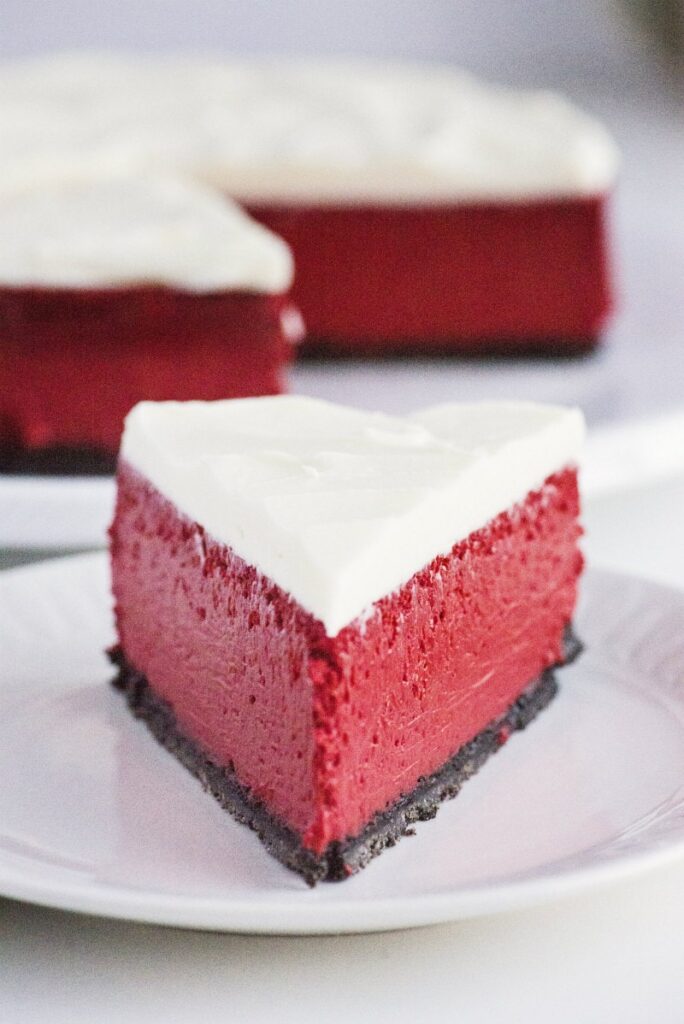 slice of red velvet cheesecake on plate with frosting 