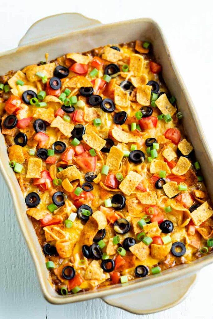 taco casserole in pan topped with olives, and toppings