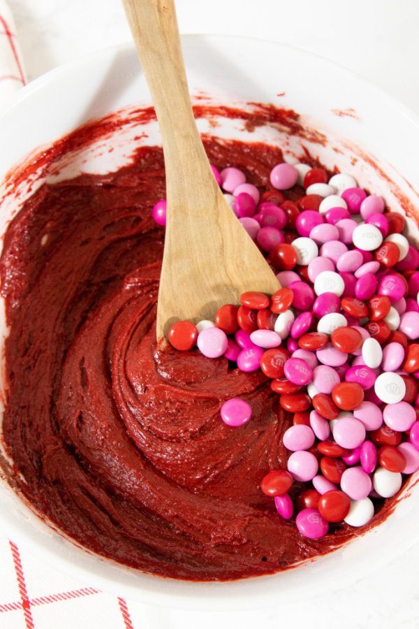 cookie batter with candies in it and wooden spoon