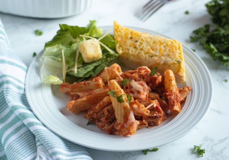 chicken rigatoni on plate with salad and bread