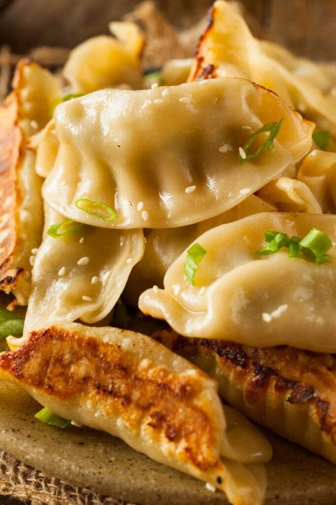 pile of potstickers on a plate with garnish 