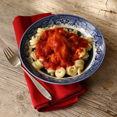 bowl of pasta on a wooden table with fork by it 