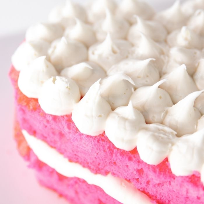 side view of pink cake with frosting on top 