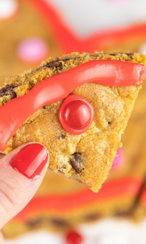 cut out piece of valentine cookie being held in hand 