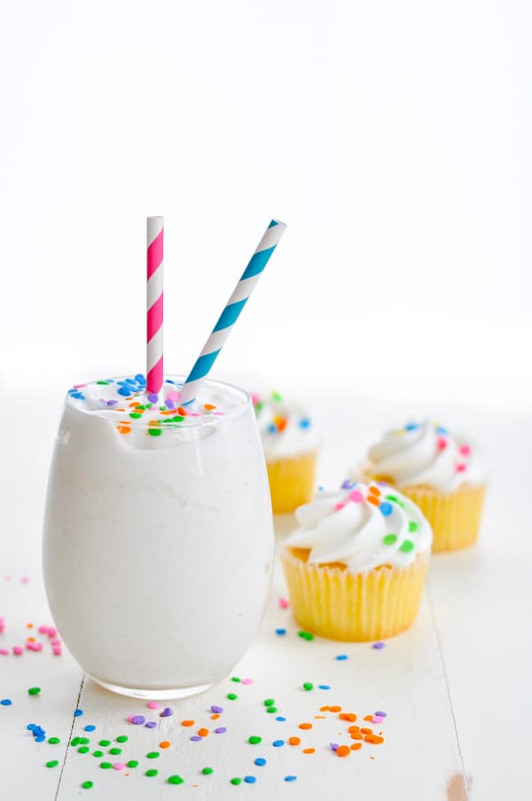 smoothie on table with cupcakes behind it 