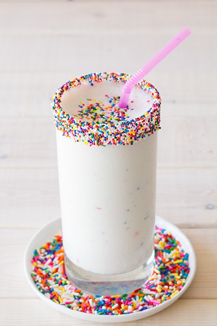 milkshake with sprinkles and pink straw on counter 