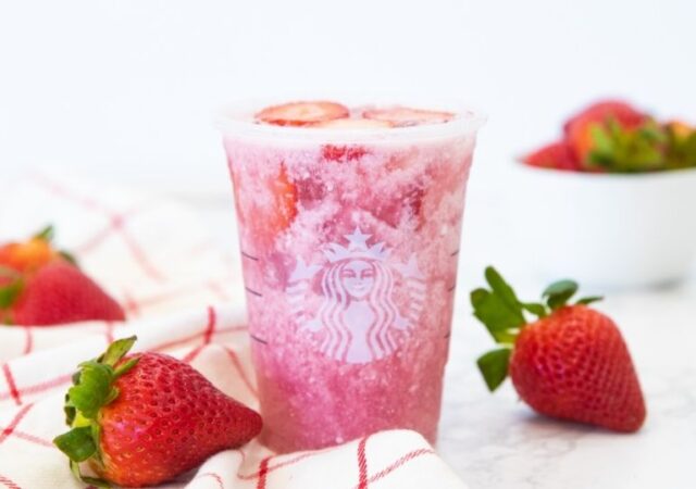 Starbucks pink drink on table with berries around it