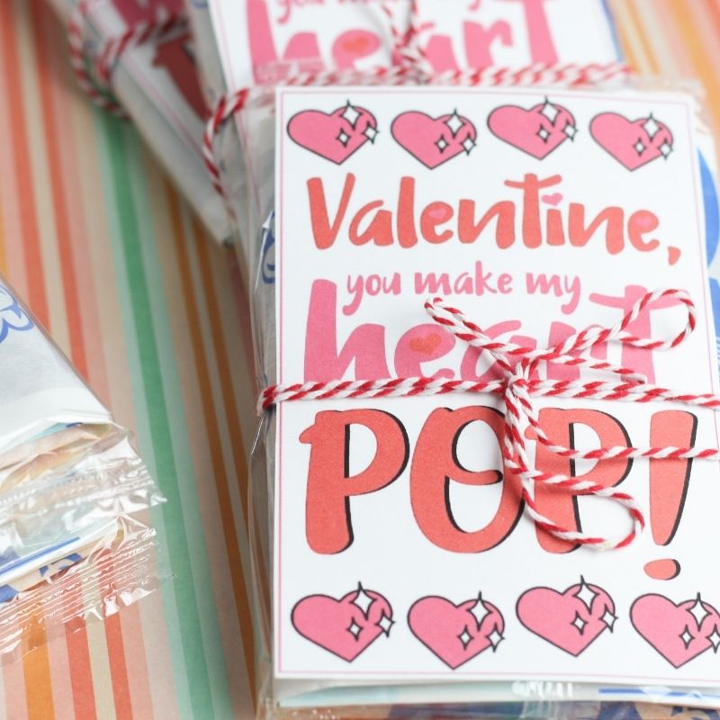 Snag this free popcorn valentine printable for gifting loved ones. This is a free printable You Make My Heart Pop Printable to use for v-day! #passion4savings #valentine #printable #freebie #free #vday #popcorn #Noncandy #freeprintable #forkids valentines on table with popcorn wrapped in ribbon