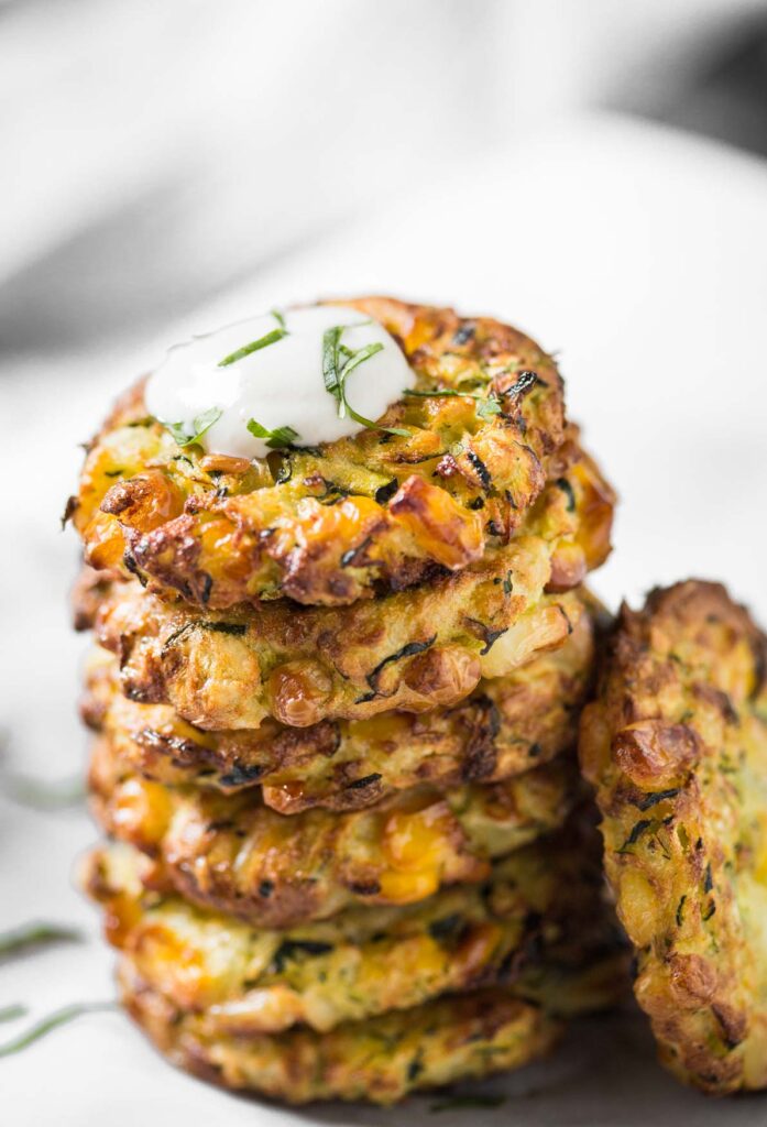 stacked zucchini fritters with topping on top 