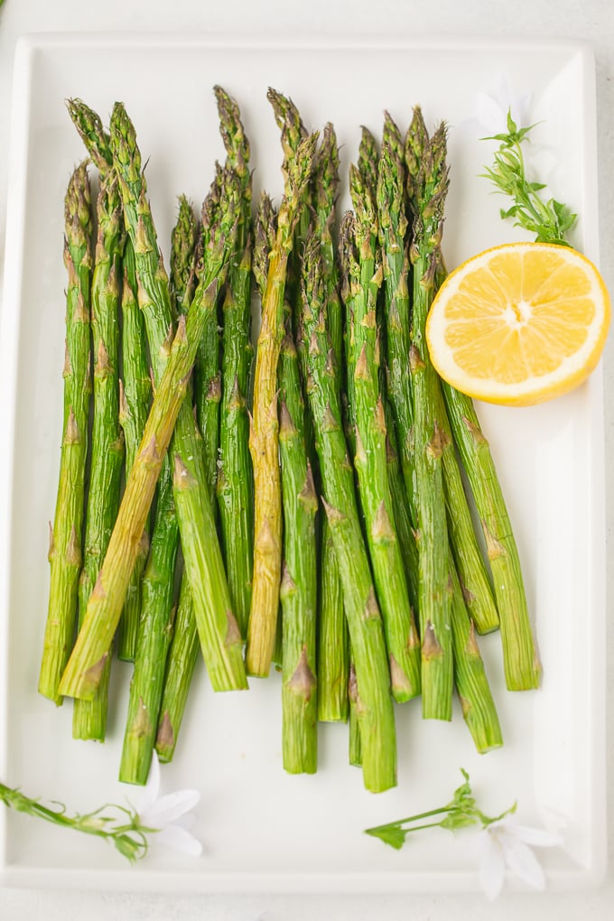 plate of asparagus with lemon on side 