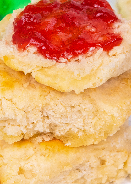 a close up of sprite biscuits made with sour cream stacked on top of each other with jam or jelly on top