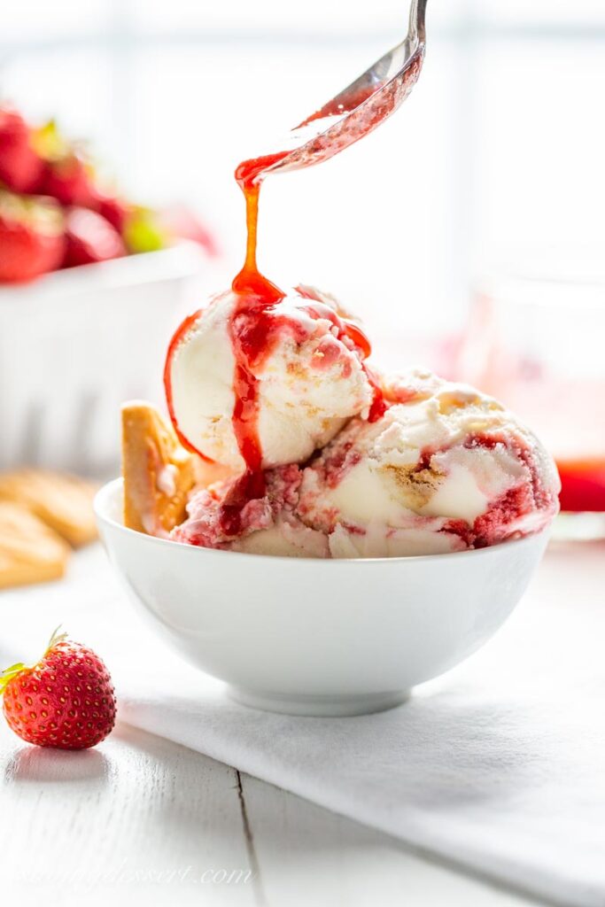 strawberry syrup pouring on a bowl of ice cream 