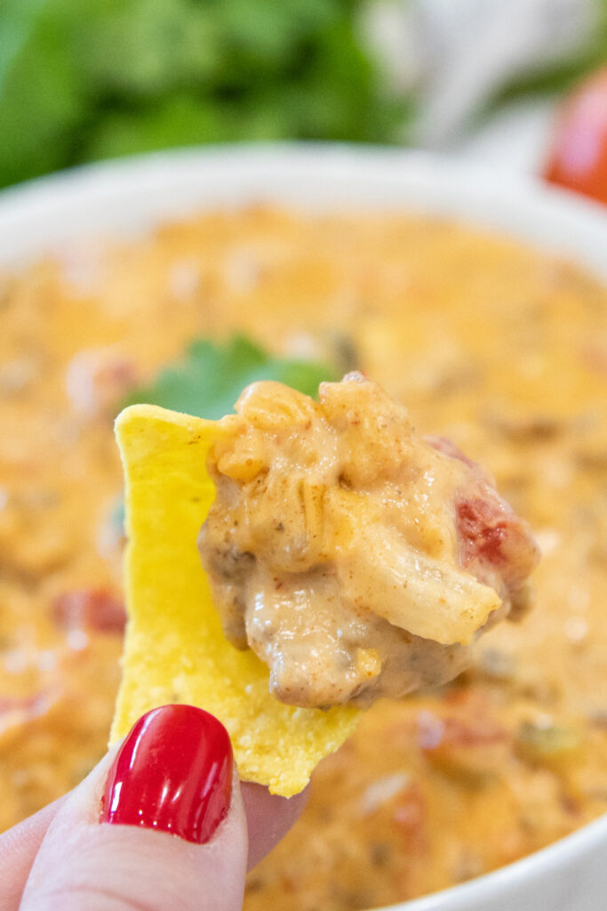 smoked queso dip on a tortilla chip in the hand