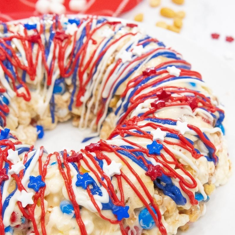 Serve up this delicious sweet patriotic popcorn cake for Memorial day or the 4th of July. An easy no bake dessert to make and serve up. #passion4savings #Popcorn #cake #Nobake #easy #best #homemade #marshmallow #dessert #fun #memorialday popcorn cake on a platter