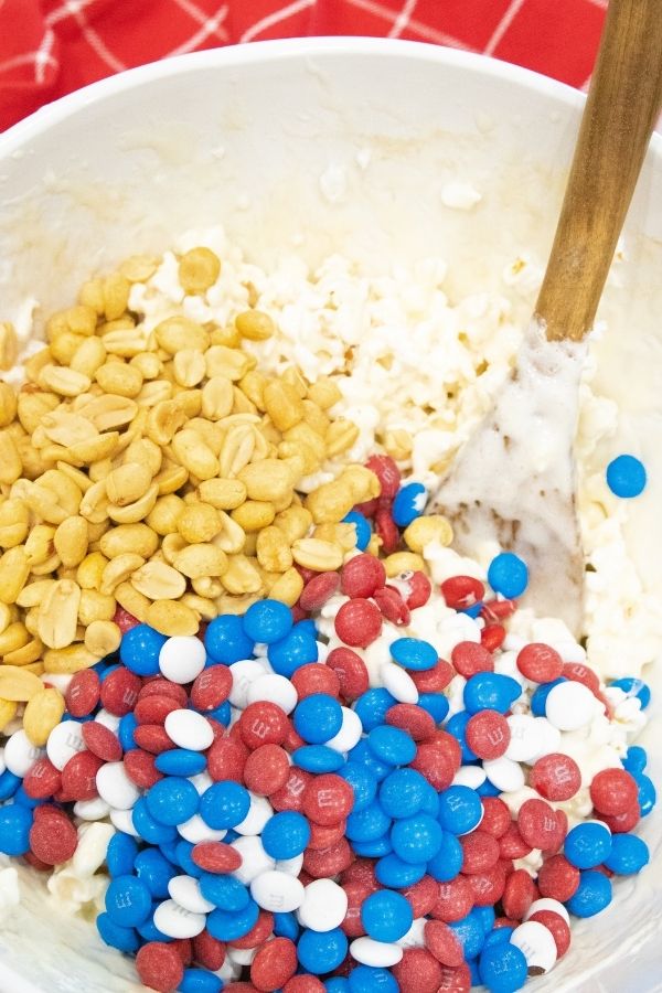 mixing up popcorn with candy and peanuts 
