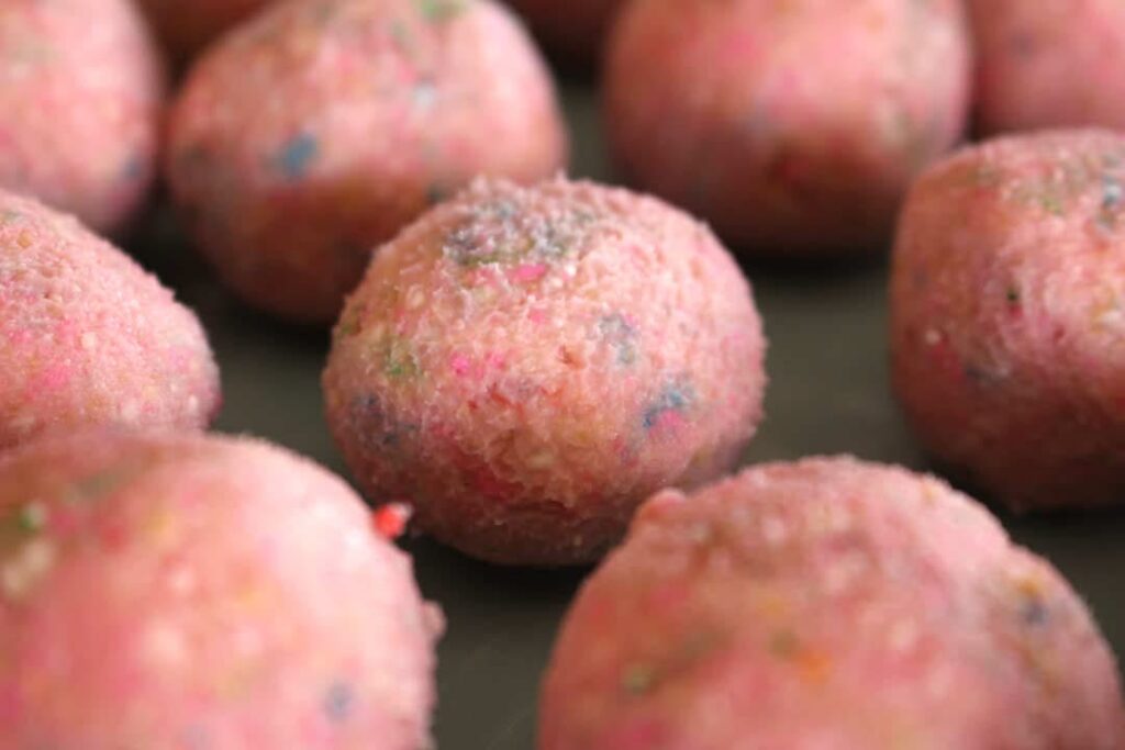 pink truffles on a baking tray lined up 