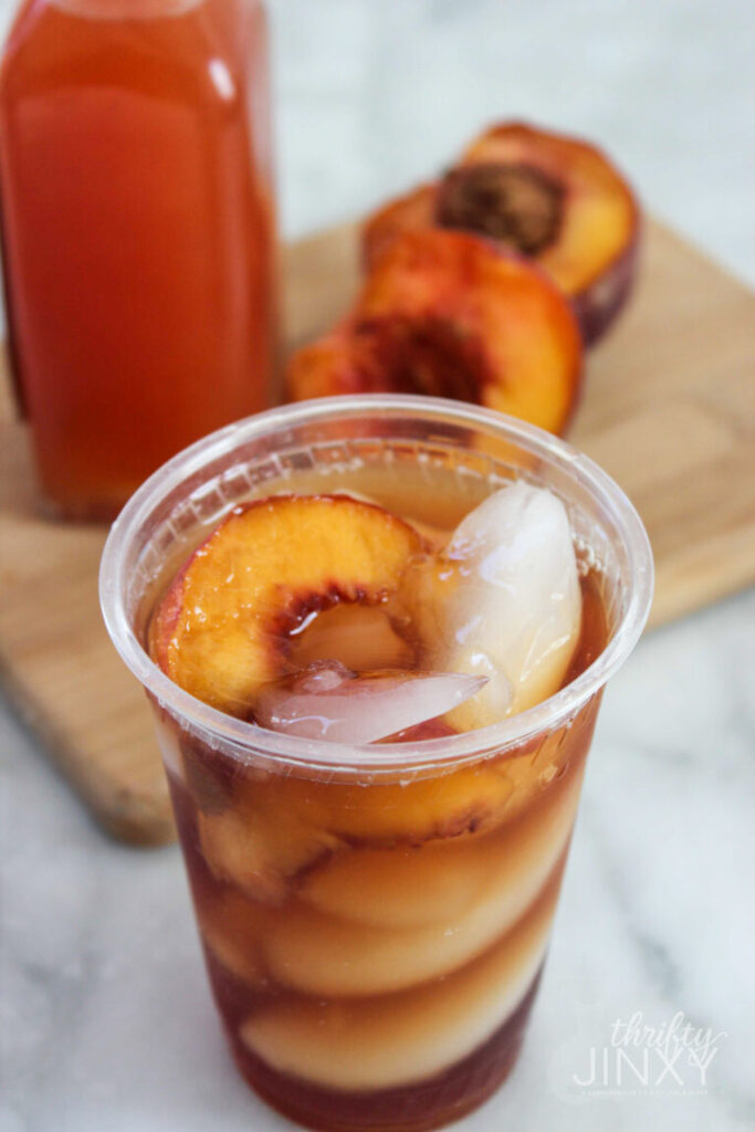 peach iced tea with ice in a plastic cup on counter 