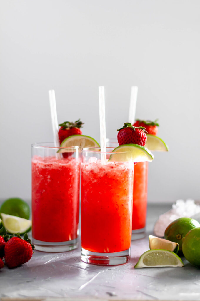 strawberry limeade in glasses with limes beside it 