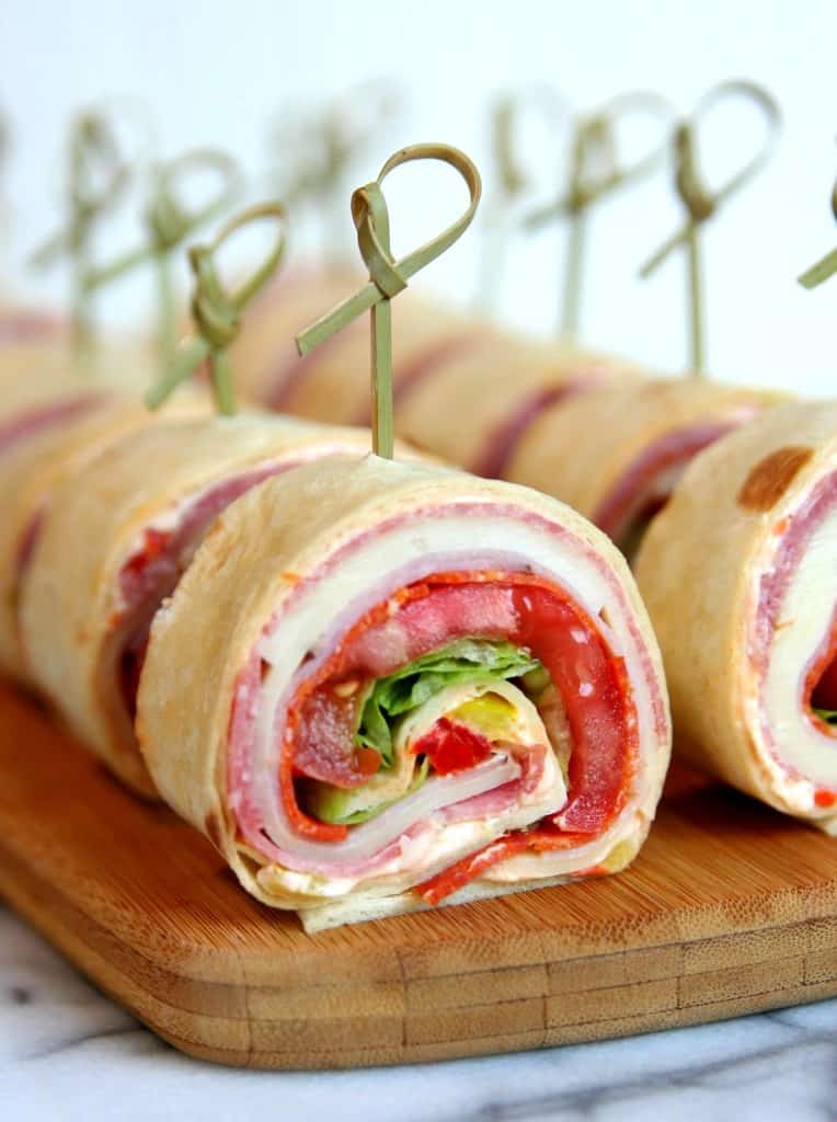 sliced italian roll ups on a wooden cutting board 