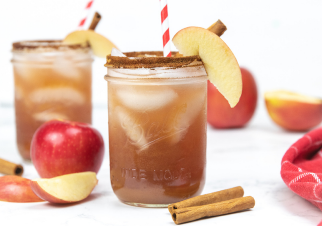 glasses with cider punch in it and apples and cinnamon sticks on the side