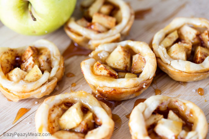 apple pies that are bite size on table with apple behind it 